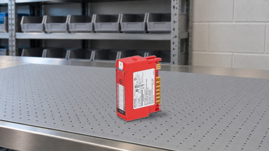 Red 1734-IB8S safety input module standing on a steel workbench in front of warehouse shelving