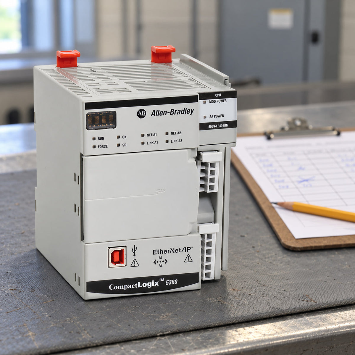 CompactLogix 5380 controller on a workbench beside a clipboard with a handwritten paper downtime log